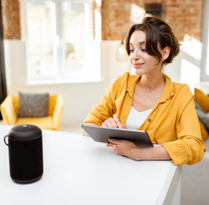 Futuristic living room featuring a sleek smart home hub on a coffee table, ambient smart lighting, and a robotic vacuum in operation