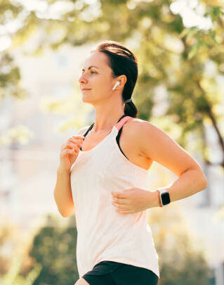 A person running outdoors with a smartwatch clearly visible on their wrist, demonstrating active use of wearable tech