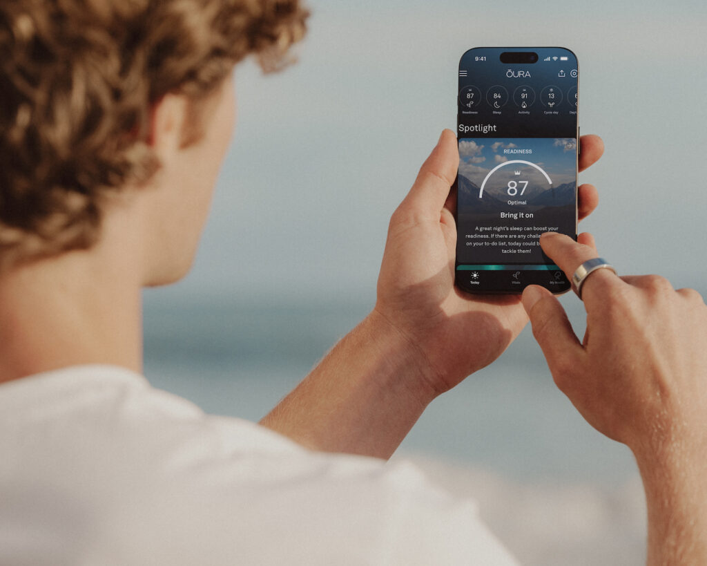 Wearable Tech in 2025: Your Guide to Smartwatches, Rings, and Beyond A sleek, matte black smart ring on a person's finger, next to a smartphone displaying sleep tracking data