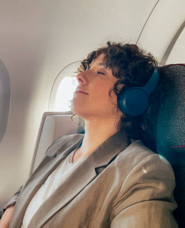 Person using noise-canceling headphones on a flight.