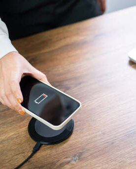 The Best Tech Gifts Under $50 for Everyone on Your List A sleek wireless charging pad charging a smartphone on a modern desk.